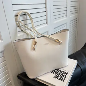 Minimalist white faux leather tote bag with gold logo lettering and slim shoulder straps