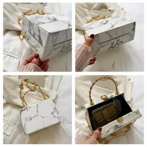 Detail view of marble pattern box bag with bamboo handle and gold chain strap