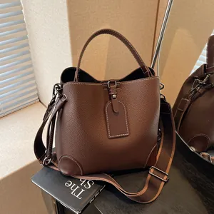 Deep brown pebble leather bucket bag with white stitching and adjustable wide shoulder strap