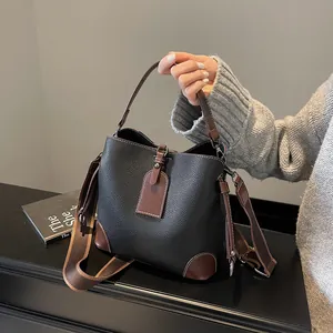 Chic black and brown leather bucket bag for women featuring stylish wide fabric strap