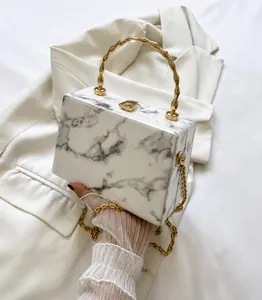 Detail of white marble textured box bag with gold bamboo handle and chain strap