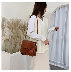 Schicke braune Handtasche mit Steinmuster am Modell mit modischem breitem Schultergurt