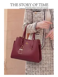 Détail d'un sac à main bordeaux en cuir grainé avec logo kangourou doré et breloque