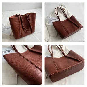 Detail view of large brown tote bag with crocodile pattern texture and double handles