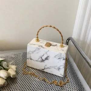 Detail of marble pattern box clutch with golden bamboo handle and chain strap