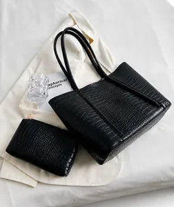 Detail of black crocodile pattern tote bag set with matching zipper pouch on white fabric