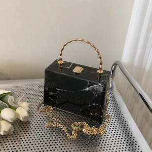 Detail of black marble pattern crossbody bag with golden bamboo handle and chain strap