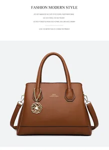 Detail of brown tote bag with lychee texture, gold lettering and camellia pendant