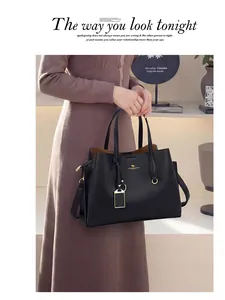 Détail du sac à main noir en cuir grainé avec logo kangourou doré et pendentif métal