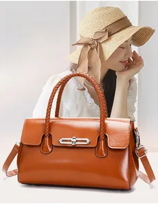 Detail view of brown glossy leather handbag with woven handle and elegant metal lock