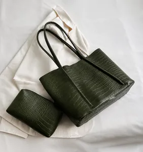 Detail of green crocodile embossed tote bag with matching zippered pouch on white shirt
