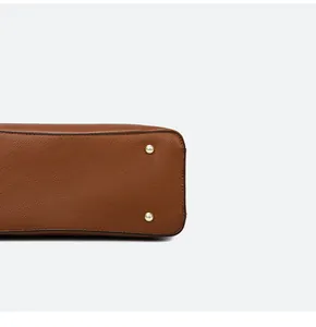 Detail shot of brown lychee leather tote base with protective gold metal rivets