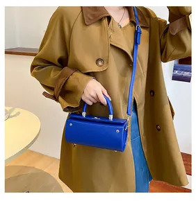 Detail of Klein blue cylindrical crossbody bag with top handle and adjustable strap