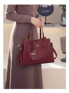 Détail de cabas en cuir bordeaux avec logo doré et doubles poignées élégantes