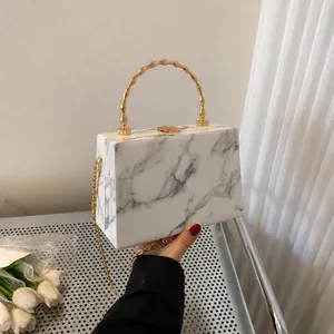 Close-up of marble pattern crossbody bag with golden bamboo handle and chain strap