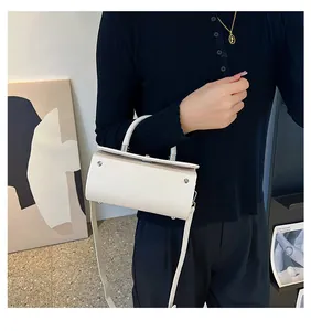 Detail showing chic beige crossbody bag with silver lock and thin handle on model