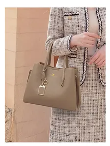 Détail d'un sac cabas en cuir kaki avec logo doré et structure latérale en accordéon