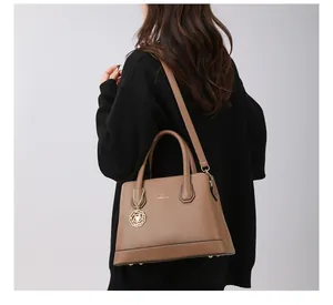 Detail of brown litchi pattern tote bag with gold hardware and camellia pendant