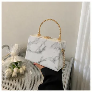 Detail of white marble pattern clutch with a gold bamboo handle and chain strap