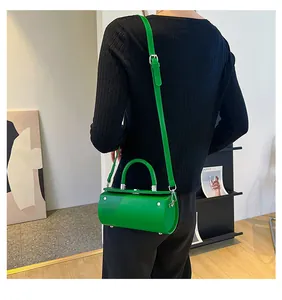 Detail view of the bright green cylindrical handbag showing the smooth finish and metal studs