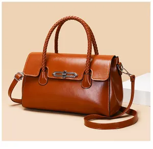 Detail of caramel brown crossbody bag with woven handles and silver metal twist lock closure