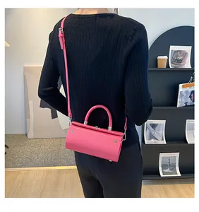 Detail view of the bright pink cylindrical handbag showing the smooth texture and silver hardware