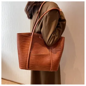 Detail of dark brown tote bag with crocodile texture and long shoulder straps