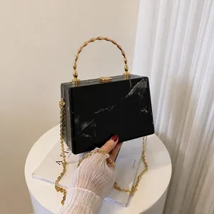 Detail of marble pattern acrylic box bag with golden bamboo handle and chain strap