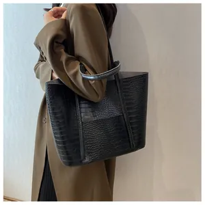 Detail of black faux crocodile leather tote bag featuring glossy texture and spacious design