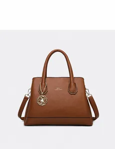 Detail of brown lychee grain leather tote bag with gold logo and flower charm