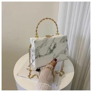 Detail of marble pattern box bag with gold bamboo handle and metallic chain strap