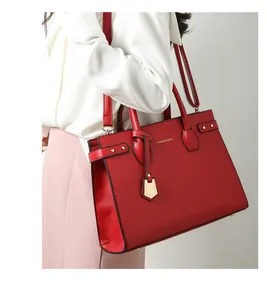 Borsa tote rossa in pelle a grana con manici e tracolla mostrata su una modella