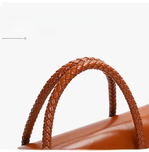 Detailed close-up of woven leather handles on a brown vintage crossbody handbag