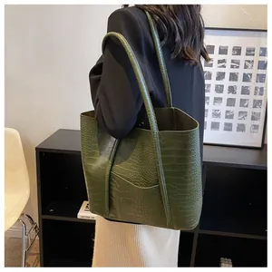 Detail of dark green tote bag featuring crocodile pattern texture and large capacity