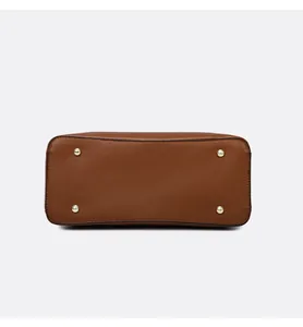Detail view of brown pebbled leather bag bottom with four protective gold metal studs