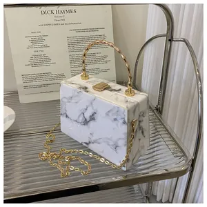 Detail of marble pattern handbag with gold bamboo handle and metallic chain strap
