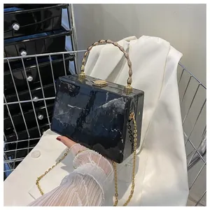 Detail of black marble pattern crossbody box bag with golden bamboo handle and chain strap