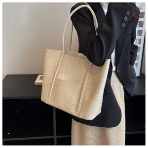 Crocodile pattern tote bag in cream finish shown as a shoulder bag on a model