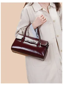 Detail of burgundy glossy tote bag with woven handles and metal buckle on trench coat