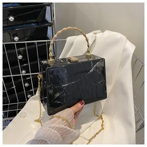 Detail of black marble box clutch bag with gold bamboo handle and metal chain