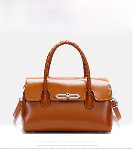 Brown glossy leather handbag featuring woven handles and stylish silver chain hardware