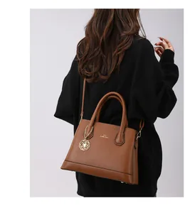 Detail of dark brown pebble leather tote bag with XTI branding and rose charm