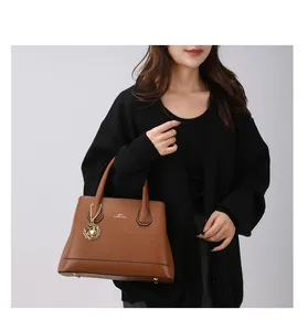 Detailed close-up of brown pebbled leather tote bag with gold logo and flower charm