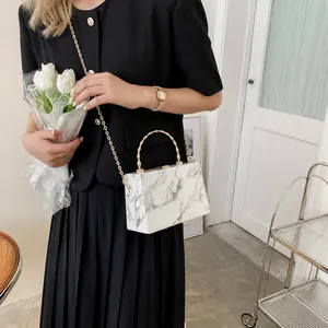 Detail view of marble texture crossbody bag with gold bamboo handle and chain