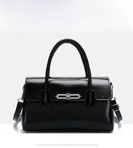 Detail of black handbag showing woven top handle and silver metal turn-lock closure