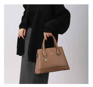 Detail of a brown lychee leather tote bag with golden hardware and floral charm
