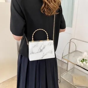 Detail of marble pattern hard case bag with golden bamboo handle and chain strap