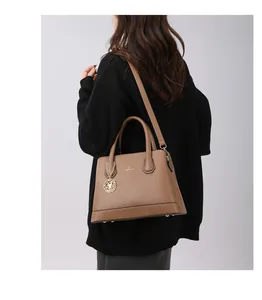 Detail view of caramel brown PU leather tote with classic lettering and gold rose charm