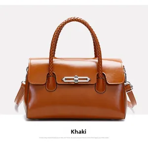 Detail of khaki leather handbag with woven handle, metal clasp and detachable shoulder strap