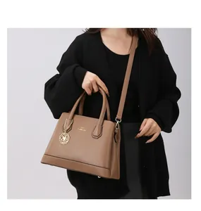 Detailed macro view of the brown leather tote bag with golden logo and flower charm